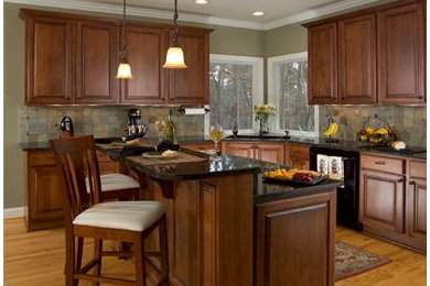 Elegant kitchen photo in Raleigh with an undermount sink, dark wood cabinets, granite countertops, black appliances and an island