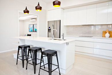 This is an example of a small modern galley eat-in kitchen in Townsville with a double-bowl sink, recessed-panel cabinets, white cabinets, quartz benchtops, grey splashback, glass sheet splashback, stainless steel appliances, ceramic floors and with island.