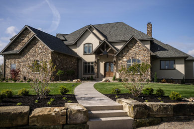 Huge elegant beige two-story stone house exterior photo in Other with a shingle roof and a gray roof