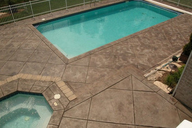 Mid-sized minimalist backyard stamped concrete and rectangular lap hot tub photo in Other