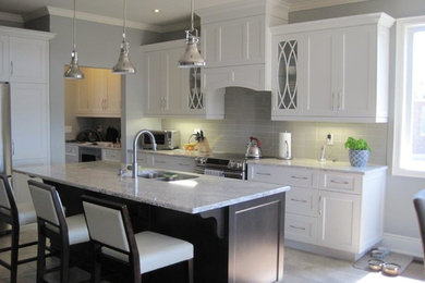 Example of a mid-sized transitional galley travertine floor and beige floor eat-in kitchen design in Toronto with a double-bowl sink, shaker cabinets, white cabinets, marble countertops, gray backsplash, glass tile backsplash, stainless steel appliances and an island