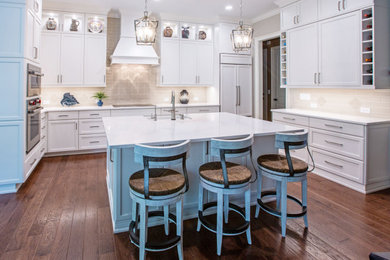 Example of a large transitional u-shaped medium tone wood floor open concept kitchen design in Atlanta with a farmhouse sink, white cabinets, beige backsplash, stainless steel appliances, an island and white countertops