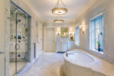 This is an example of a traditional master bathroom in New York with raised-panel cabinets, white cabinets, a freestanding tub, an alcove shower, beige walls, marble floors, an undermount sink, marble benchtops, white floor and a sliding shower screen.