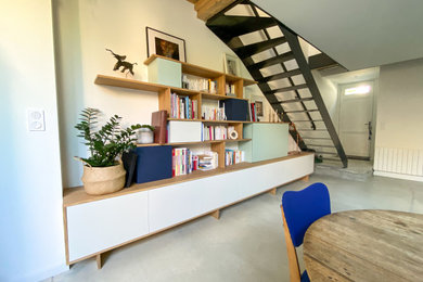 Idée de décoration pour un salon design de taille moyenne et ouvert avec une bibliothèque ou un coin lecture, un mur blanc, sol en béton ciré, aucune cheminée, un téléviseur dissimulé, un sol gris et poutres apparentes.
