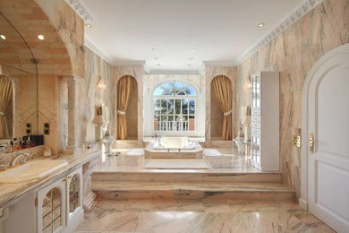 Example of a large classic master marble floor drop-in bathtub design in Philadelphia with white cabinets, multicolored walls and marble countertops