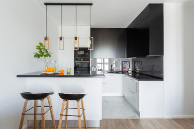 Design ideas for a scandinavian l-shaped kitchen in Moscow with flat-panel cabinets, grey splashback, glass sheet splashback, black appliances, white floor, black benchtop, a single-bowl sink, black cabinets and a peninsula.