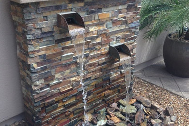 Photo of a mid-sized modern partial sun backyard stone landscaping in Phoenix.
