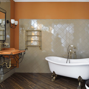 Elegant master beige tile brown floor claw-foot bathtub photo in Moscow with a two-piece toilet, orange walls, a drop-in sink and orange countertops
