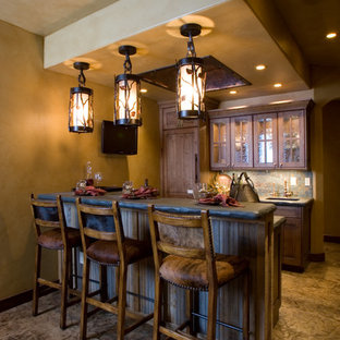 デンバーの小さいラスティックスタイルのおしゃれな着席型バー (アンダーカウンターシンク、レイズドパネル扉のキャビネット、中間色木目調キャビネット、ベージュキッチンパネル、テラコッタタイルのキッチンパネル) の写真