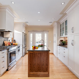 Exemple d'une arrière-cuisine parallèle chic avec un évier posé, un placard à porte shaker, des portes de placard blanches, un plan de travail en granite, une crédence orange, un électroménager en acier inoxydable, un sol en bois clair et un îlot central.