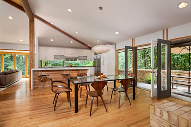 This is an example of a midcentury open plan dining in Detroit with white walls and light hardwood floors.