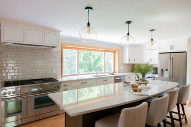 Example of a large transitional l-shaped light wood floor and brown floor eat-in kitchen design in Boston with an undermount sink, shaker cabinets, white cabinets, quartz countertops, white backsplash, ceramic backsplash, stainless steel appliances, an island and white countertops