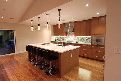 Inspiration for a large modern medium tone wood floor kitchen remodel in San Francisco with a drop-in sink, medium tone wood cabinets, gray backsplash, subway tile backsplash, stainless steel appliances and an island