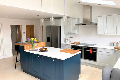 Design ideas for a large contemporary kitchen/diner in Other with a belfast sink, shaker cabinets, blue cabinets, white splashback, stainless steel appliances, an island, white worktops and a vaulted ceiling.
