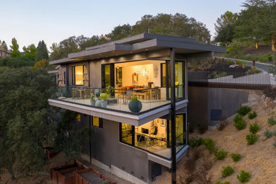 Diseño de fachada de casa gris actual de tamaño medio de dos plantas con revestimiento de estuco y tejado plano