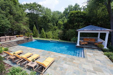 Design ideas for a mid-sized transitional backyard rectangular lap pool in Baltimore with a pool house and natural stone pavers.