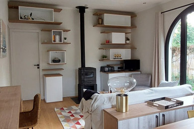Foto de sala de estar abierta costera de tamaño medio sin televisor con paredes blancas, suelo de madera clara, estufa de leña y suelo beige
