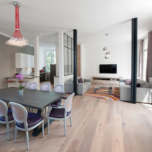 Exemple d'une salle à manger ouverte sur le salon tendance avec un mur gris et un sol en bois clair.