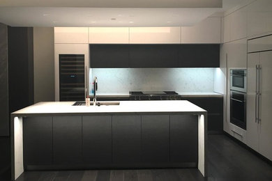 Inspiration for a medium sized modern galley enclosed kitchen in Chicago with a submerged sink, flat-panel cabinets, grey cabinets, composite countertops, white splashback, stone slab splashback, stainless steel appliances, dark hardwood flooring and an island.