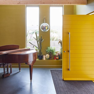 Réalisation d'un hall d'entrée bohème de taille moyenne avec un mur jaune, un sol en linoléum, une porte simple, une porte jaune et un sol noir.