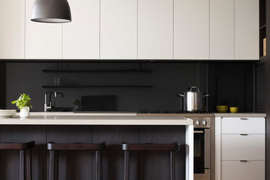 Contemporary single-wall open plan kitchen in Melbourne with an undermount sink, quartz benchtops, black splashback, glass sheet splashback, stainless steel appliances, medium hardwood floors, flat-panel cabinets and with island.