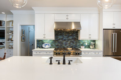 Mid-sized beach style u-shaped medium tone wood floor open concept kitchen photo in Miami with an undermount sink, shaker cabinets, white cabinets, quartz countertops, blue backsplash, stainless steel appliances, an island and glass tile backsplash