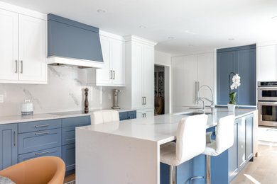 Example of a large transitional l-shaped light wood floor and beige floor eat-in kitchen design in Toronto with a drop-in sink, blue cabinets, quartz countertops, white backsplash, quartz backsplash, an island, white countertops, shaker cabinets and paneled appliances