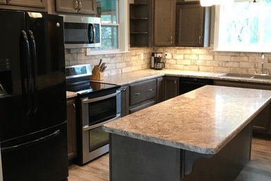 Mid-sized elegant l-shaped vinyl floor and multicolored floor eat-in kitchen photo in Other with a drop-in sink, recessed-panel cabinets, dark wood cabinets, laminate countertops, multicolored backsplash, porcelain backsplash, black appliances and an island