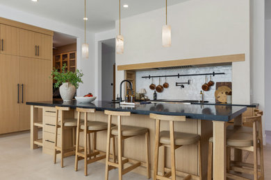 Inspiration for a transitional beige floor kitchen remodel in Salt Lake City with an undermount sink, flat-panel cabinets, light wood cabinets, white backsplash, paneled appliances, an island and black countertops