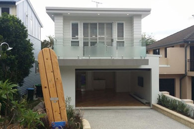 Photo of a mid-sized beach style split-level white house exterior in Sydney with mixed siding, a flat roof and a metal roof.