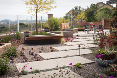 Mid-sized contemporary courtyard full sun xeriscape in San Diego with a retaining wall and concrete pavers for spring.