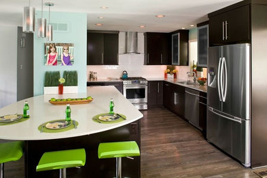 Inspiration for a large modern l-shaped medium tone wood floor open concept kitchen remodel in DC Metro with an undermount sink, flat-panel cabinets, dark wood cabinets, solid surface countertops, white backsplash, ceramic backsplash, stainless steel appliances and an island
