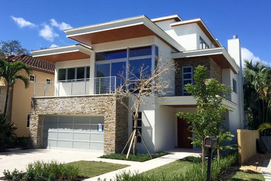 Inspiration for a contemporary beige three-story stone flat roof remodel in Miami