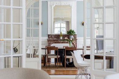 Cette image montre une grande salle à manger traditionnelle fermée avec un mur bleu, parquet clair, une cheminée standard, un manteau de cheminée en pierre, un sol beige et boiseries.