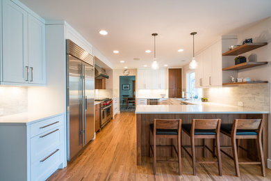 Example of a large transitional u-shaped medium tone wood floor eat-in kitchen design in Denver with an undermount sink, shaker cabinets, yellow cabinets, quartz countertops, gray backsplash, terra-cotta backsplash, stainless steel appliances and an island
