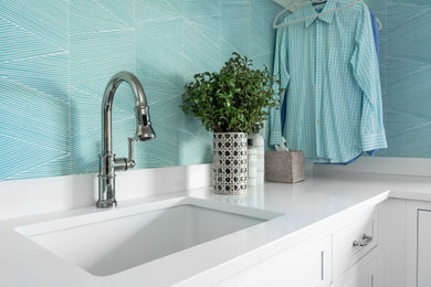 Inspiration for a large coastal u-shaped dark wood floor, brown floor and wallpaper dedicated laundry room remodel in Providence with an undermount sink, shaker cabinets, white cabinets, quartz countertops, white backsplash, quartz backsplash, blue walls, a side-by-side washer/dryer and white countertops