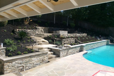Large elegant backyard stone and custom-shaped lap pool photo in Other