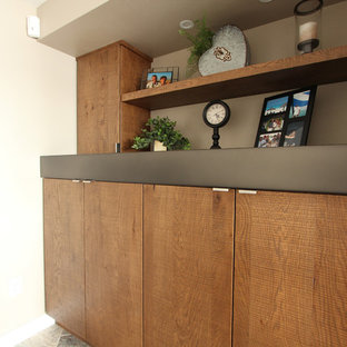 他の地域の中サイズのラスティックスタイルのおしゃれな地下室 (半地下 (ドアあり)、ベージュの壁、ライムストーンの床、標準型暖炉、石材の暖炉まわり、グレーの床) の写真