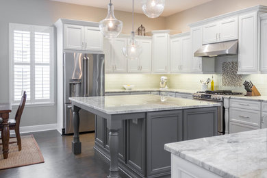Inspiration for a transitional dark wood floor and brown floor kitchen remodel in Tampa with white cabinets, granite countertops, white backsplash, glass tile backsplash, stainless steel appliances and an island