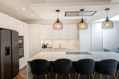 Photo of a medium sized modern l-shaped kitchen/diner in London with an island and white cabinets.