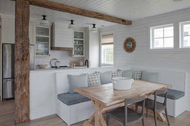 Example of a mid-sized beach style light wood floor and brown floor kitchen/dining room combo design with white walls and no fireplace
