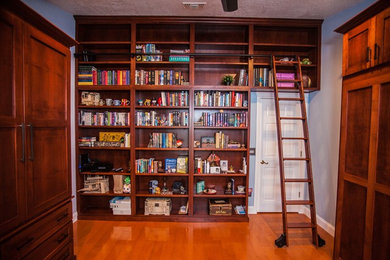 Inspiration for a mid-sized traditional home office in Orlando with a library, blue walls, medium hardwood floors, no fireplace, a built-in desk and brown floor.