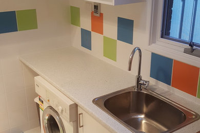 Photo of a mid-sized contemporary u-shaped utility room in Canberra - Queanbeyan with a drop-in sink, laminate benchtops, multi-coloured walls, ceramic floors and a side-by-side washer and dryer.