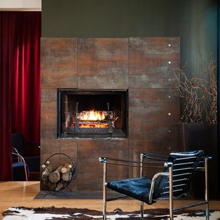 Inredning av ett modernt mellanstort allrum med öppen planlösning, med ett finrum, gröna väggar, ljust trägolv, en spiselkrans i metall och en standard öppen spis