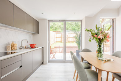 Design ideas for a medium sized modern single-wall kitchen/diner in Cambridgeshire with flat-panel cabinets, quartz worktops, white splashback, marble splashback, integrated appliances and white worktops.