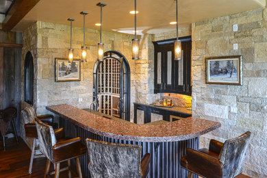 Large mountain style l-shaped dark wood floor and brown floor seated home bar photo in Other with a drop-in sink, recessed-panel cabinets, granite countertops, beige backsplash and stone tile backsplash