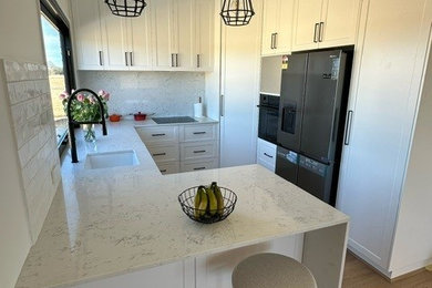 Inspiration for a small u-shaped kitchen pantry in Perth with an undermount sink, shaker cabinets, white cabinets, quartz benchtops, multi-coloured splashback, engineered quartz splashback, black appliances, medium hardwood floors, brown floor and multi-coloured benchtop.