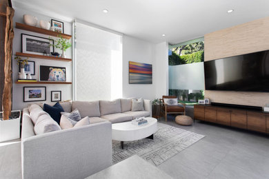Medium sized contemporary formal enclosed living room in Los Angeles with white walls, a wall mounted tv and grey floors.