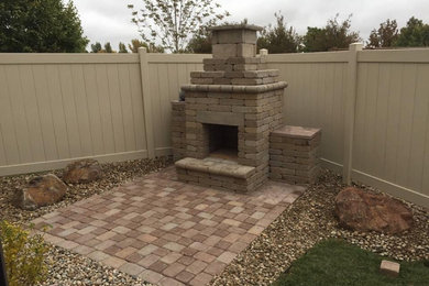 Photo of a mid-sized modern backyard concrete paver landscaping in Denver with a fireplace.