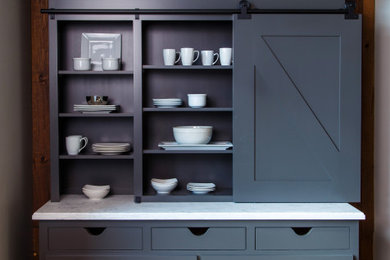Example of a country kitchen design in Other with flat-panel cabinets, gray cabinets, solid surface countertops and white countertops